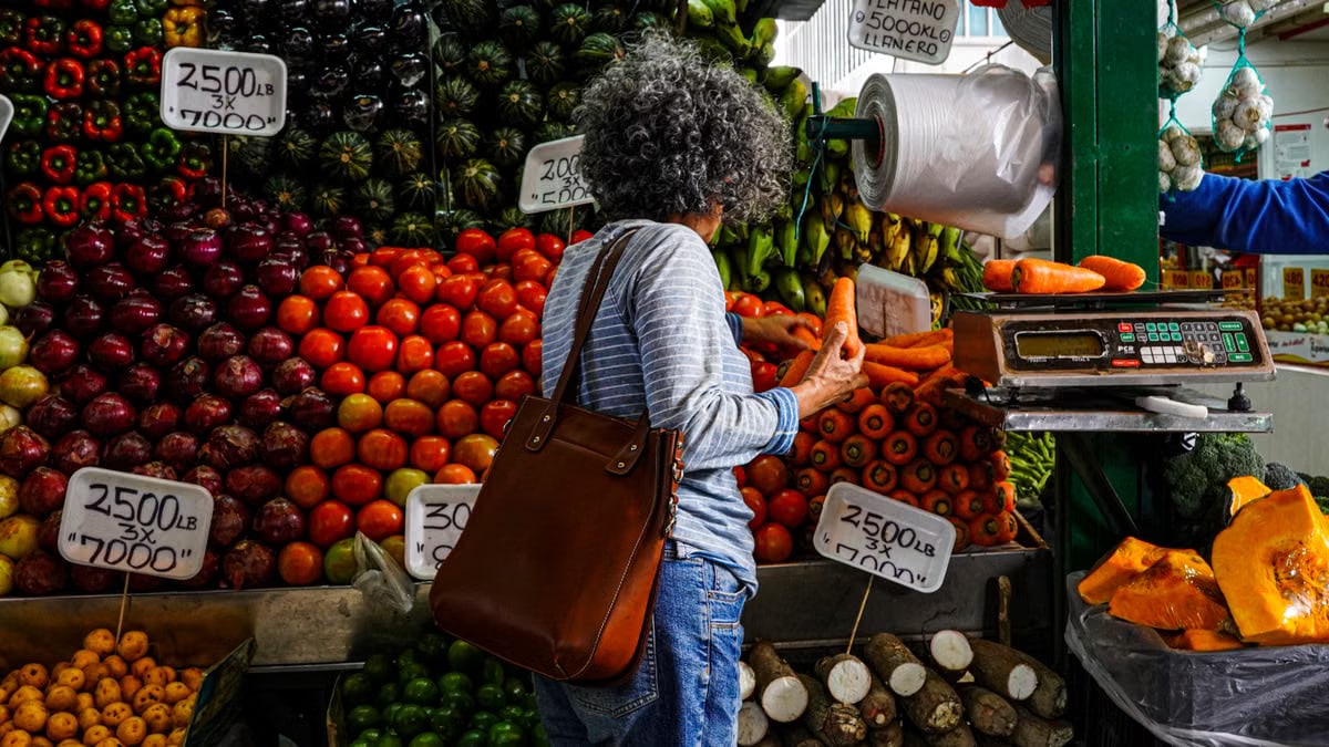 Woman shopping at a vibrant local market stall filled with fresh fruits and vegetables.